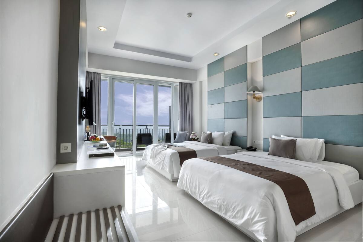 Ein modernes Hotelzimmer mit zwei Betten, einem Balkon und einem großen Fenster.