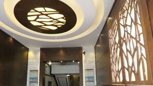 A lobby with a marble floor, a reception desk, a seating area, and a staircase leading to another floor.