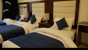A hotel room with two beds, each with a headboard, bedside tables, lamps, and pillows.