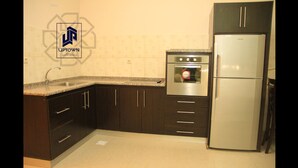 A kitchen with dark wooden cabinets, a stainless steel refrigerator, and a built-in oven.