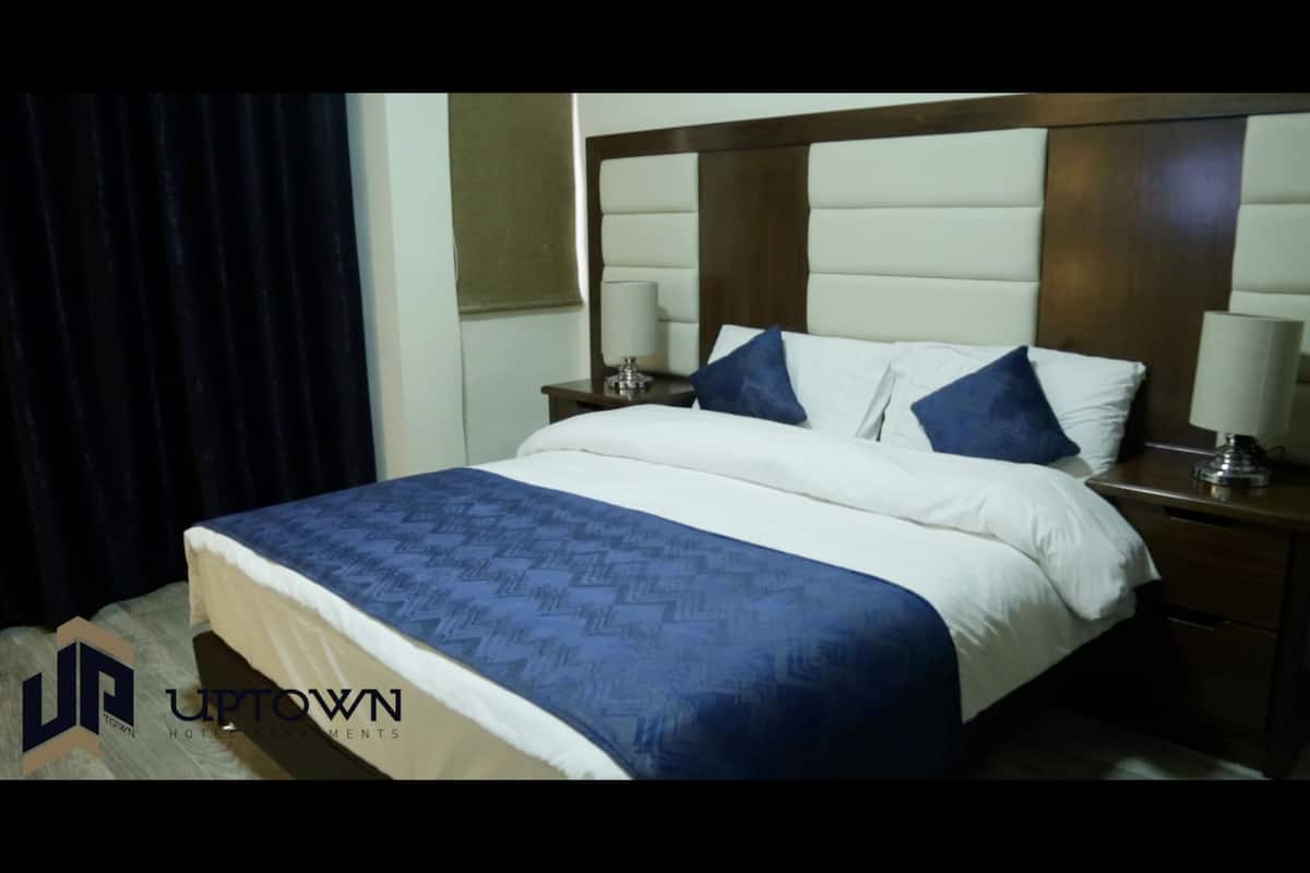 Una habitación de hotel con una cama grande, dos mesitas de noche y un cabecero.