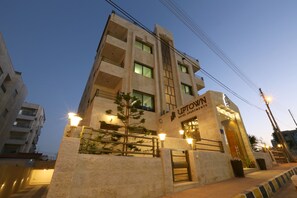 A multi-story hotel with a prominent entrance, a well-lit facade, and a clear sky in the background.