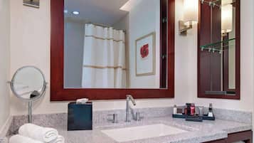 A modern bathroom with a granite countertop, a sink, a large mirror, and a towel rack.