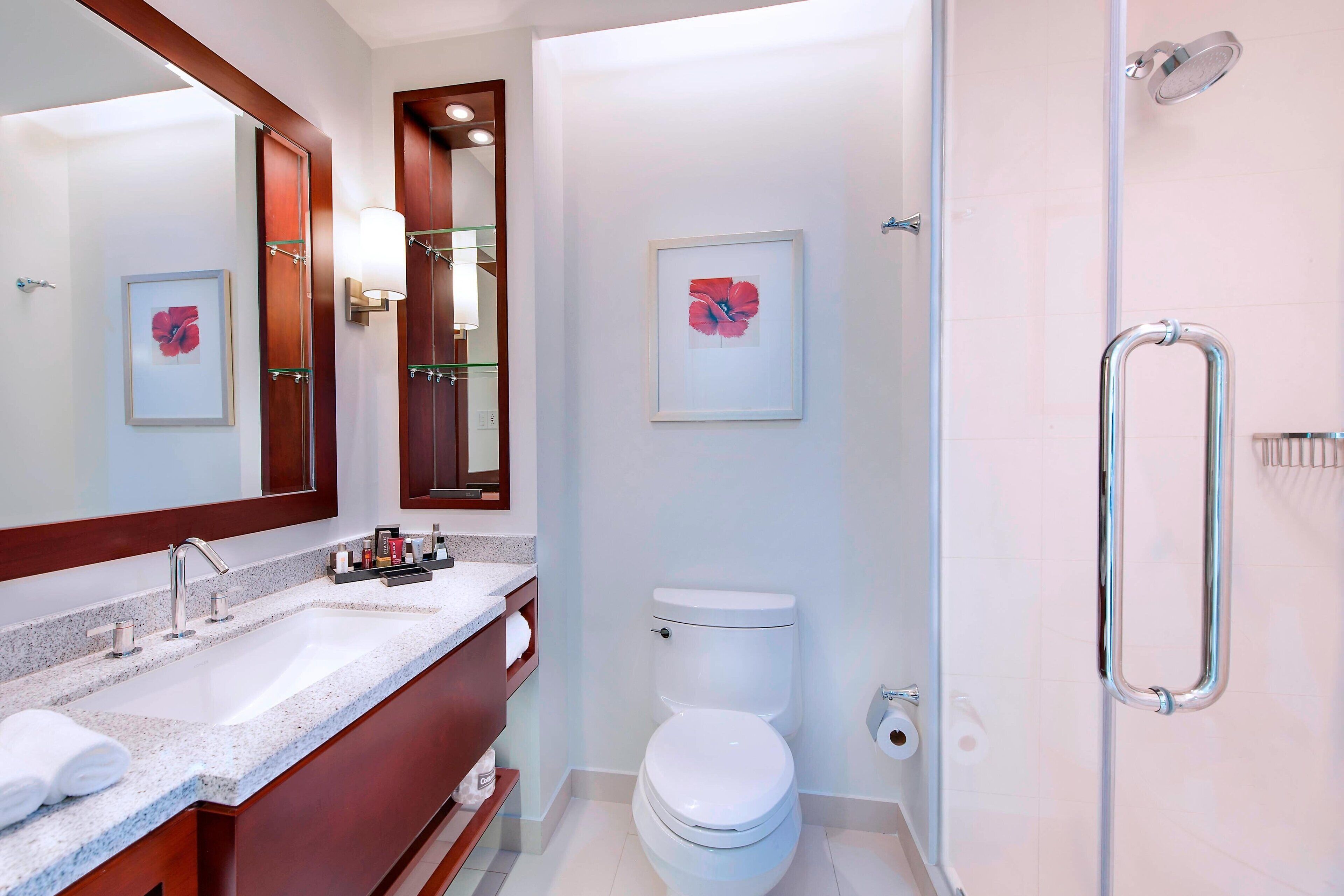 Un bagno moderno con uno specchio grande, un lavabo con piano, un water e una zona doccia.