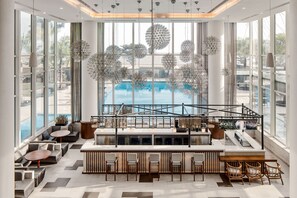 Un moderno bar con asientos, ventanas amplias e iluminación decorativa esférica.