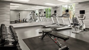 A modern gym with treadmills, elliptical machines, and free weights.