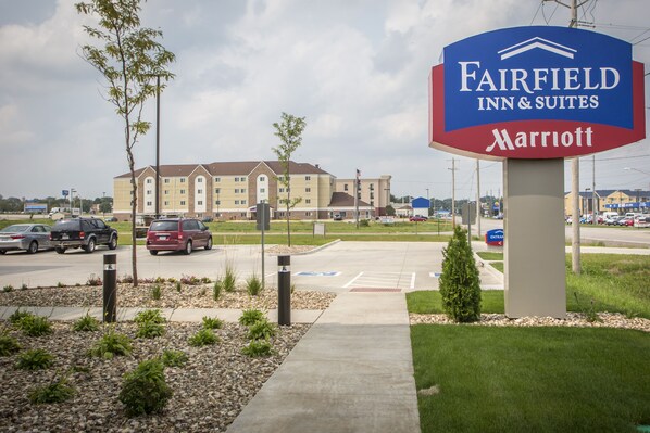 A Fairfield Inn & Suites Marriott sign with a large building in the background.