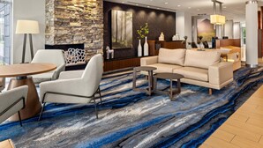 A modern lobby with a stone wall, a large painting, a sofa, and a coffee table.