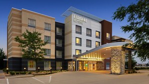 A Fairfield by Marriott hotel with a modern design, featuring a curved entrance and a stone pillar.