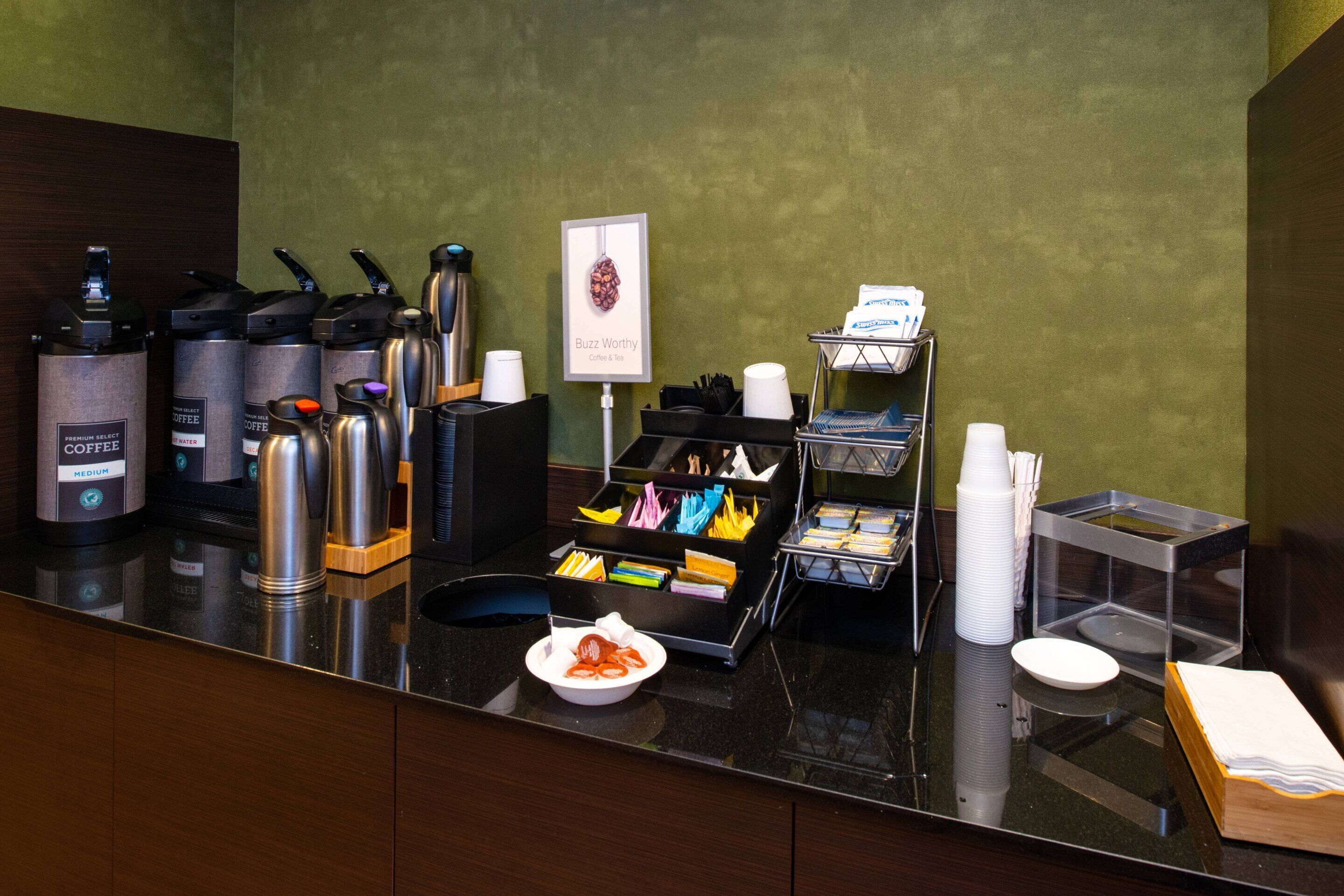 Una estación de café con varias máquinas de café, una jarra de café y un letrero que dice 