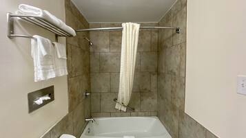 Ein Badezimmer mit einer Badewanne, einem Handtuchhalter mit gefalteten Handtüchern und einer Duschvorhang.