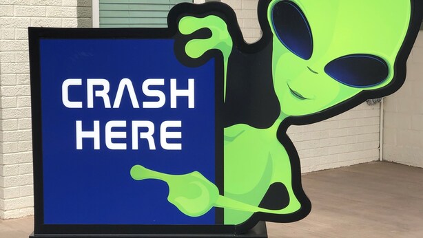 A sign with the text "CRASH HERE" and a cartoon alien figure. - Roswell Inn (Roswell)
