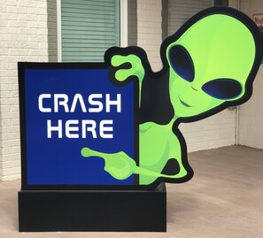 A sign with the text "CRASH HERE" and a cartoon alien figure.