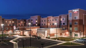 A multi-story hotel with a modern design, featuring a central entrance and multiple parking spaces.