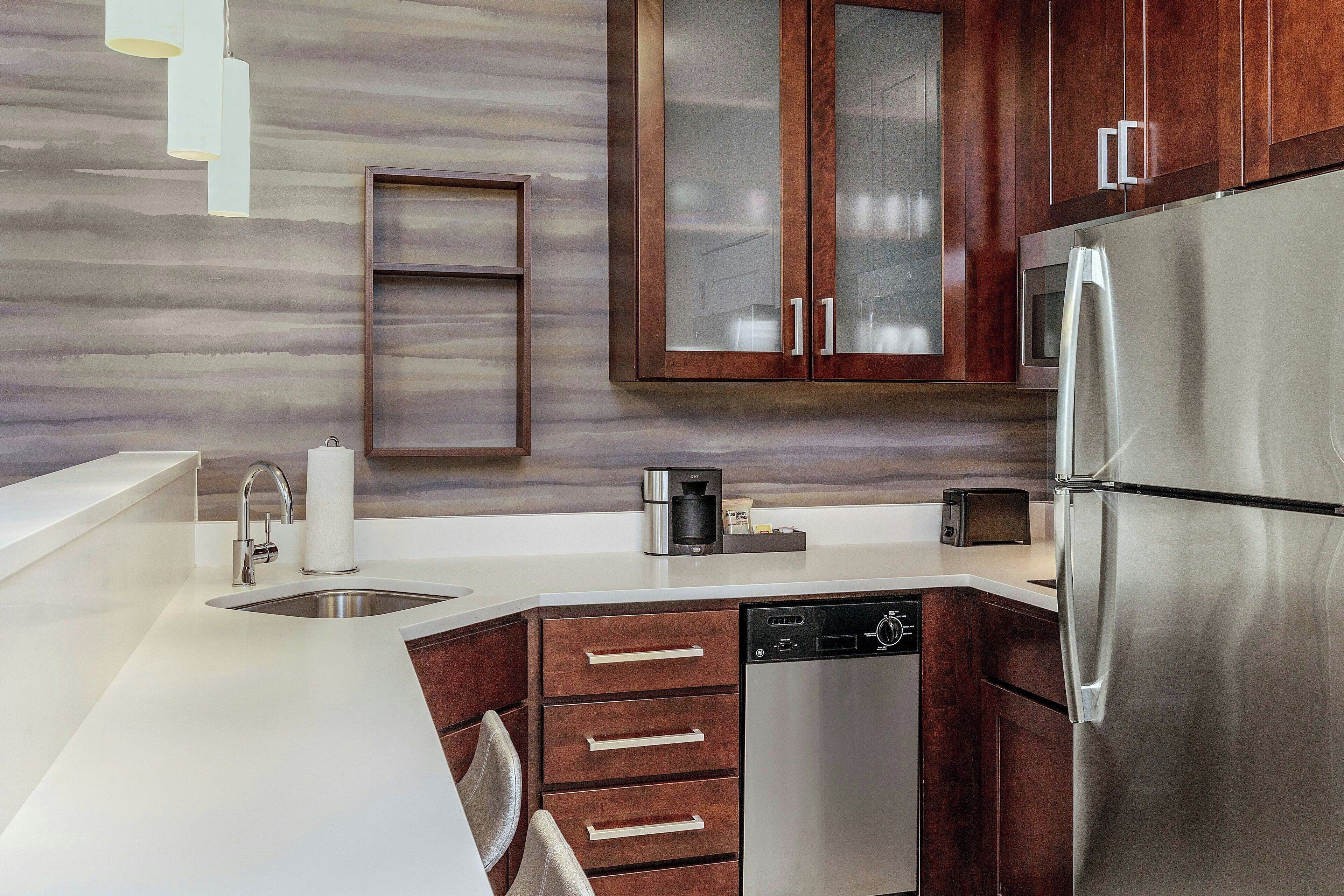 A modern kitchen with a stainless steel refrigerator, a dishwasher, and wooden cabinets.