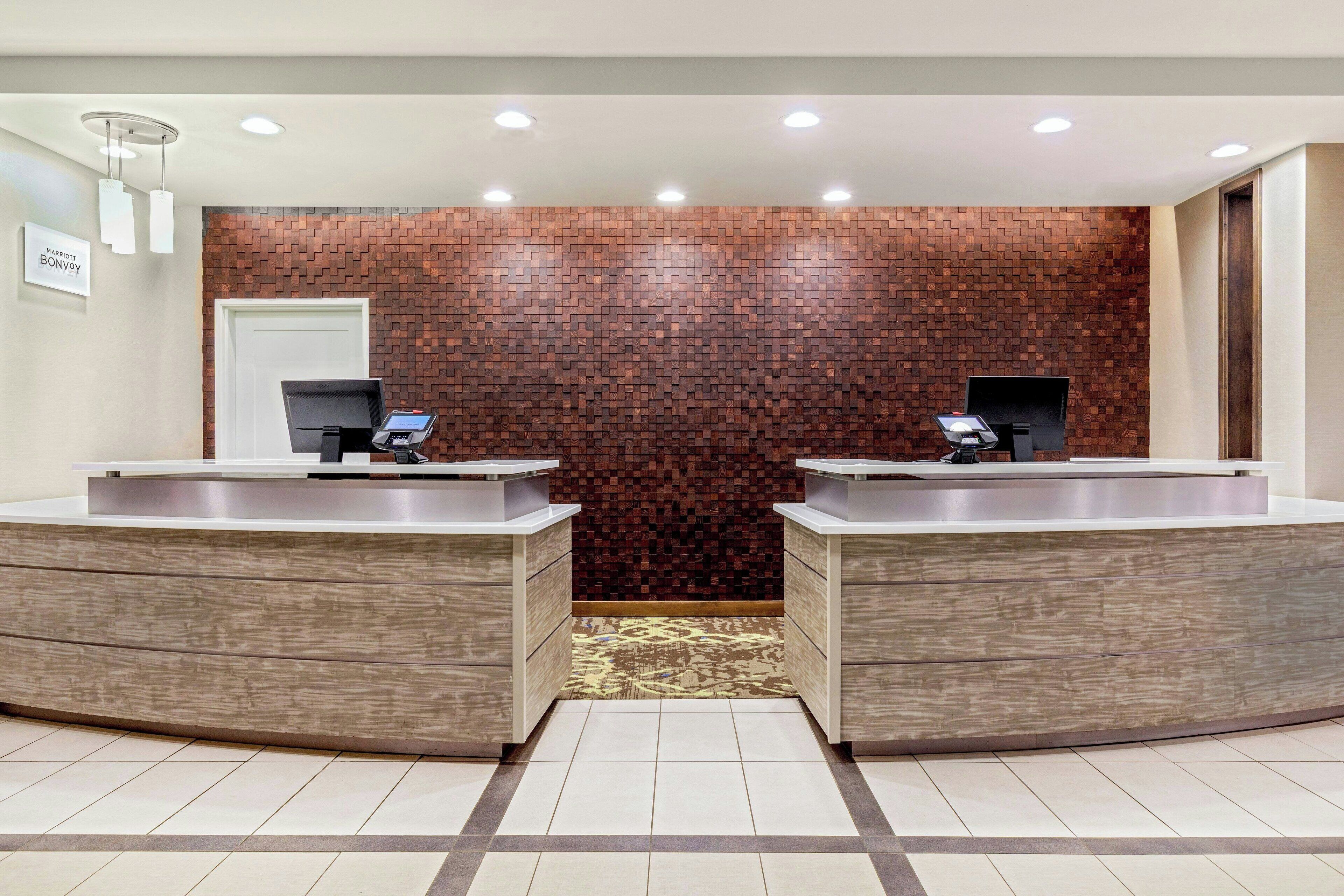 A reception area with two sinks, a patterned carpet, and a brick wall.