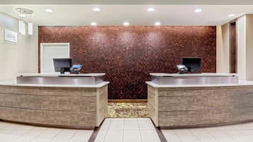 A reception area with two sinks, a patterned carpet, and a brick wall.