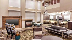 A spacious lobby with a fireplace, seating areas, and a high ceiling with hanging lights.