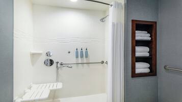 Un baño moderno con cabina de ducha, toallero empotrado y un lavamanos pequeño.