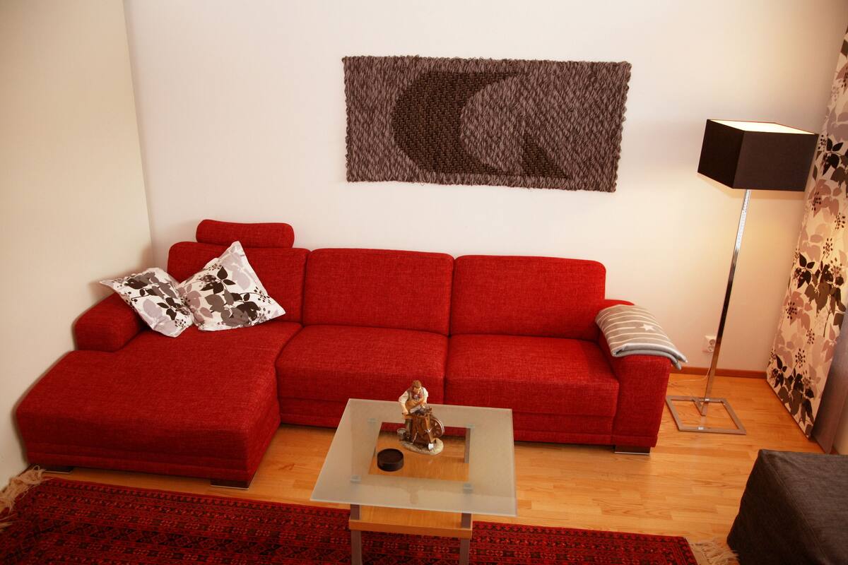 A living room with a red sofa, a glass coffee table, and a floor lamp.