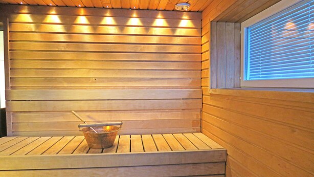 Eine Sauna mit Holzbänken und einem Eimer mit Bürste.