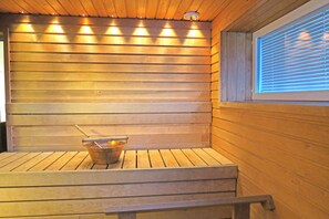 Una sauna con bancos de madera y un cubo con un cepillo.