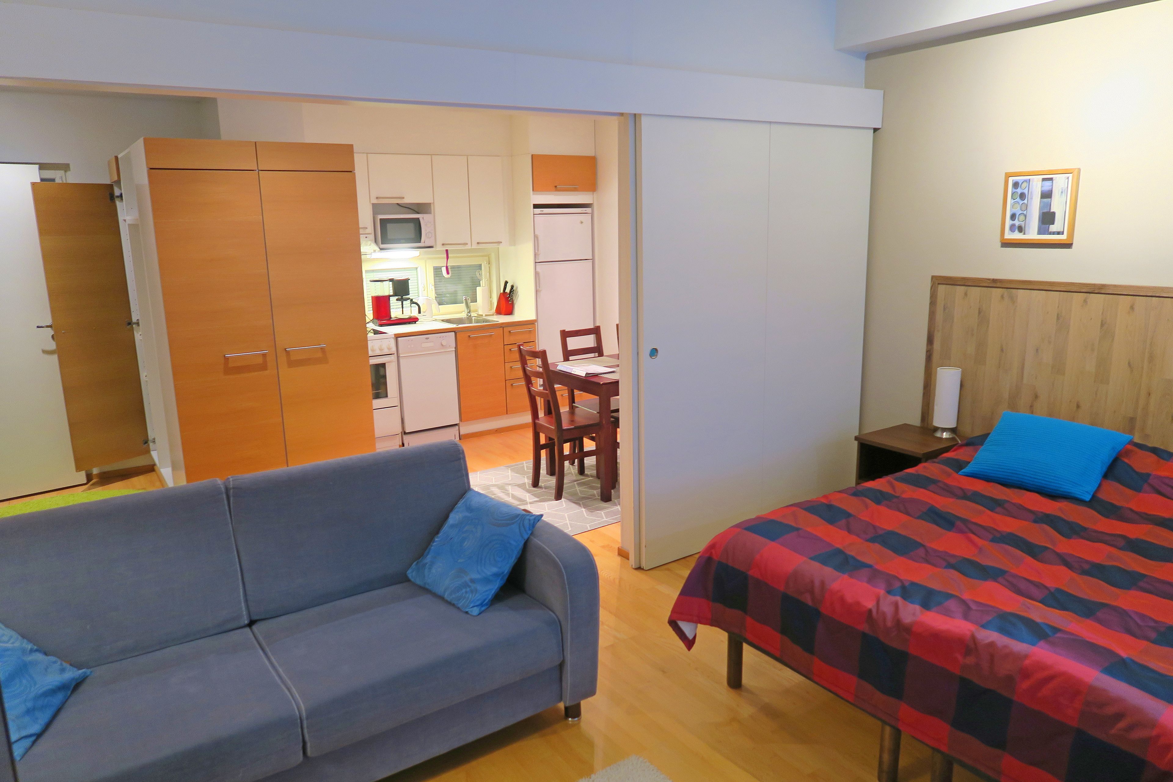 Une pièce de taille modeste comprenant un canapé, un lit, un coin cuisine et une table à manger.