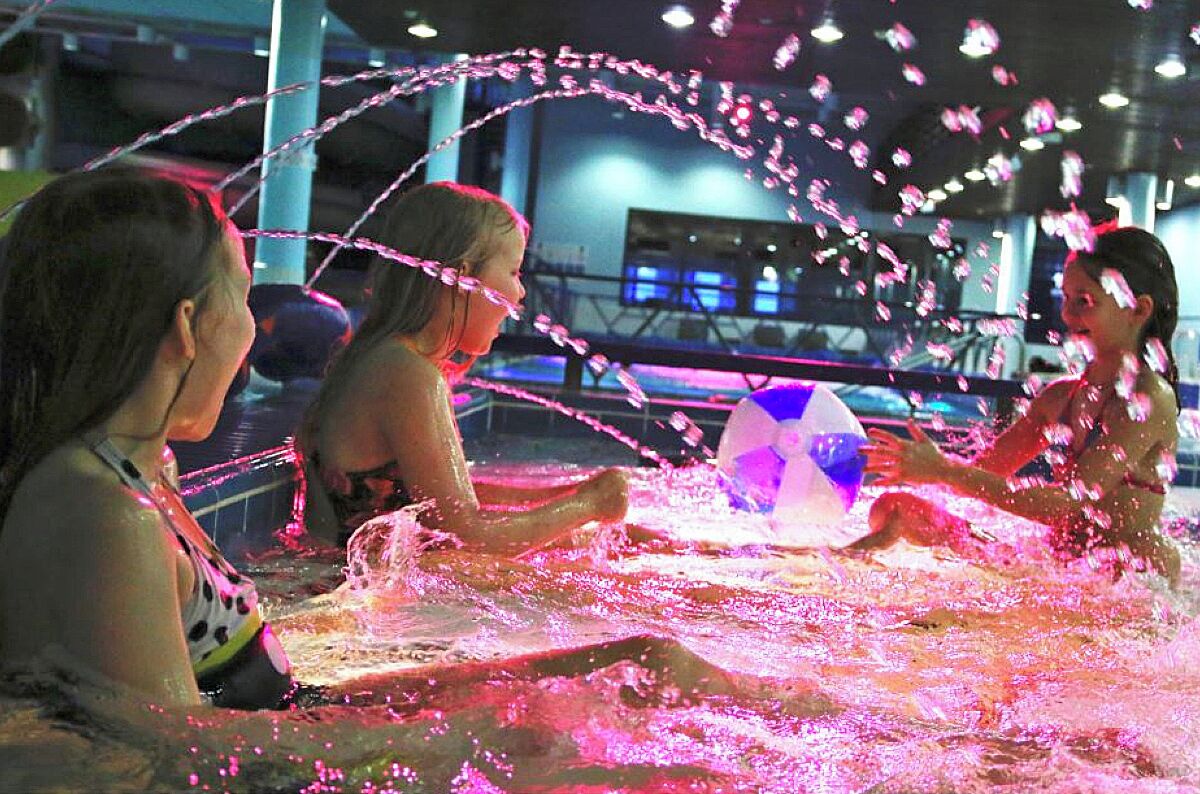 Un grupo de personas jugando con chorros de agua en un espacio interior.
