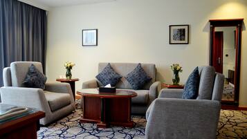 Ein Hotelzimmer mit einer Sofagarnitur, einem Couchtisch und zwei Beistelltischen mit Vasen.