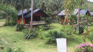 Un complexe hôtelier tropical doté de chalets en bois, entouré d’une végétation luxuriante et de palmiers.