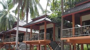 Une rangée de bâtiments de style traditionnel, dotés de balcons et entourés de palmiers.