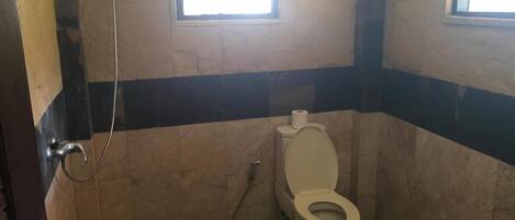 Un baño pequeño con inodoro, ducha y ventana.