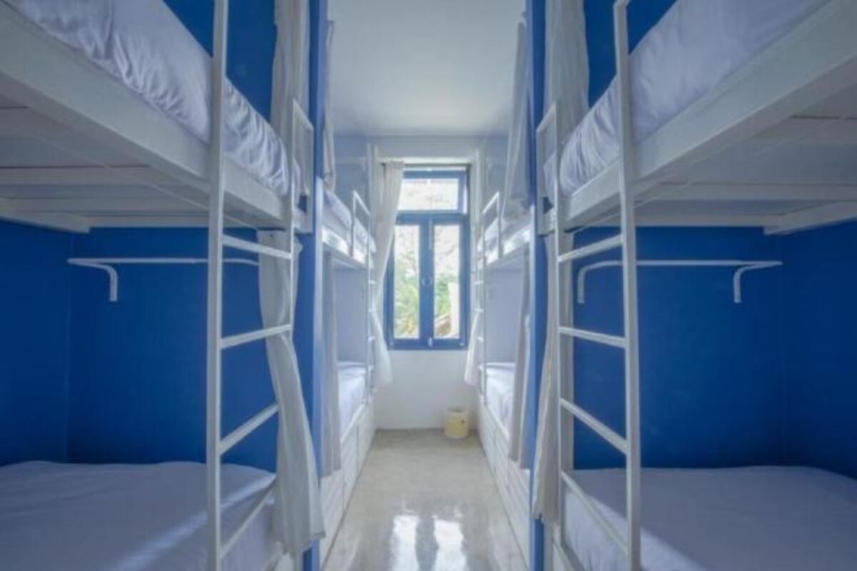 A bunk room with bunk beds, a window, and a door.