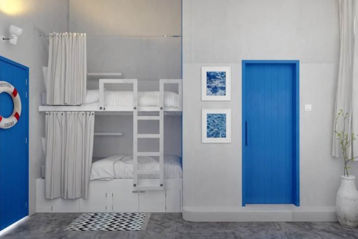 A room with bunk beds, a blue door, and two framed pictures on the wall.