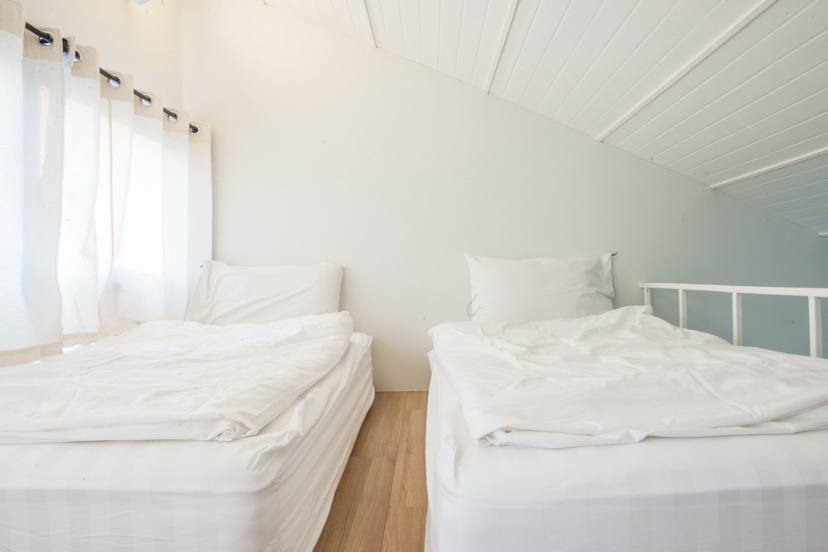 A twin room with two beds, white bedding, and a wooden floor.