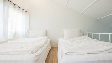 A twin room with two beds, white bedding, and a wooden floor.
