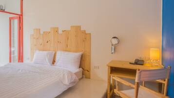 Un dormitorio con cabecera de madera, cama con ropa blanca, mesita de noche con lámpara y una silla.