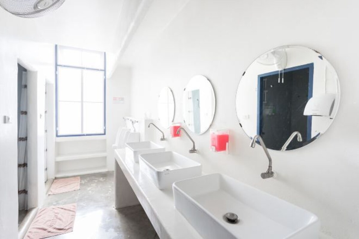A modern bathroom with multiple sinks, mirrors, and a large window.