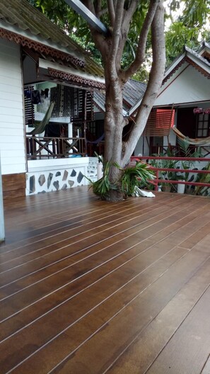 A wooden deck with a large tree in the center, surrounded by potted plants.