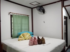 A bedroom with a bed, a window with a curtain, a ceiling fan, and a door.