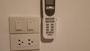 Une prise électrique murale, avec un téléphone à clapet posé à côté.