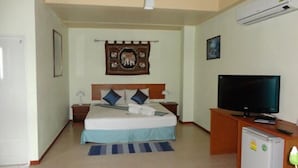 A hotel room with a bed, a television, a refrigerator, and a wall-mounted air conditioner. - VIVA on the Beach Hotel (Ko Pha-ngan)