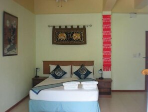 A bedroom with a bed, nightstands, a wall hanging, and a door.