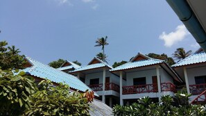 A row of buildings with blue roofs and red railings, surrounded by greenery. - Jamaica Inn Bungalow (Ko Pha-ngan)