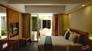 A hotel room with a bed, a TV, a desk, and a bathroom visible through an open door. - Paragon Hotel Seminyak (Keroboken Kelod)