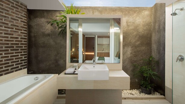 A modern bathroom with a large skylight, a bathtub, a sink, and a shower. - Paragon Hotel Seminyak (Keroboken Kelod)