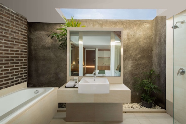 A modern bathroom with a large skylight, a bathtub, a sink, and a shower. - Paragon Hotel Seminyak (Keroboken Kelod)