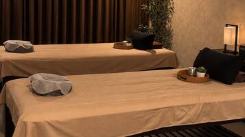 A room with two beds, a plant, a lamp, and a small table with a tray.