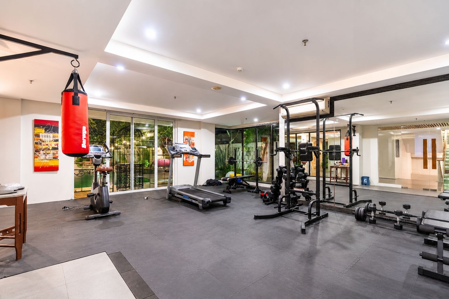 A modern gym with cardio equipment, weightlifting stations, and a punching bag.