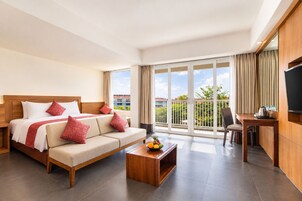 Una camera d'albergo con un letto, un divano, un tavolino, una scrivania e una televisione.